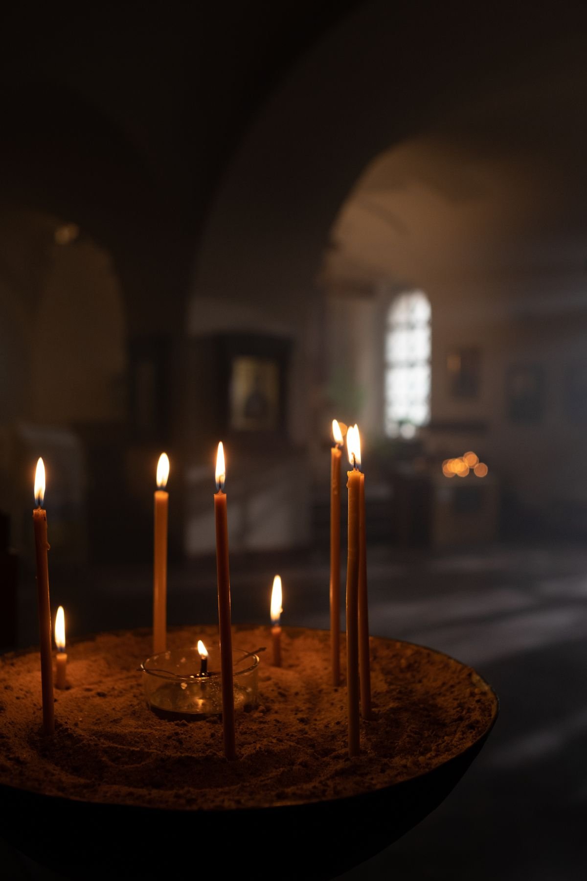 Lit candles in a quiet church, photographed by Ron Lach